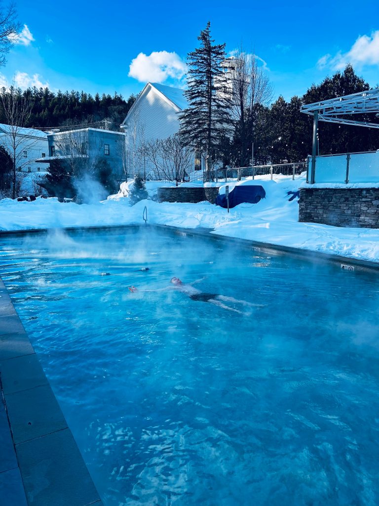 man floating in a heated pool with steam rising off of it