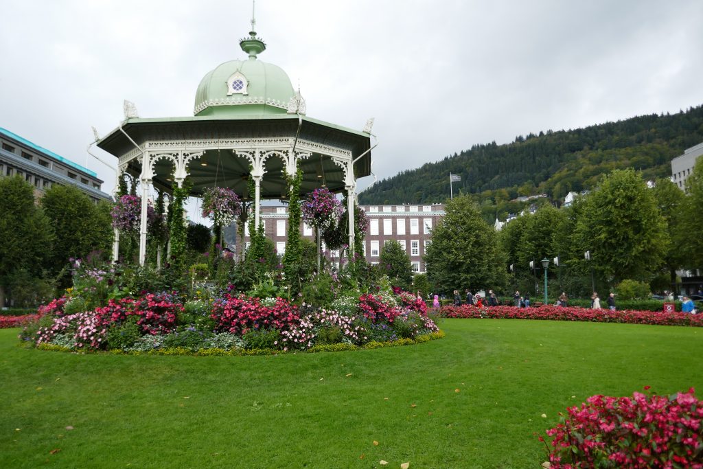 pink and white flowers around a pavilion in a green grass clearing
